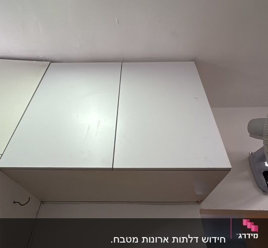 ארון אחסון עליון בגימור לבן עם דלתות ציר בצמוד לתקרה